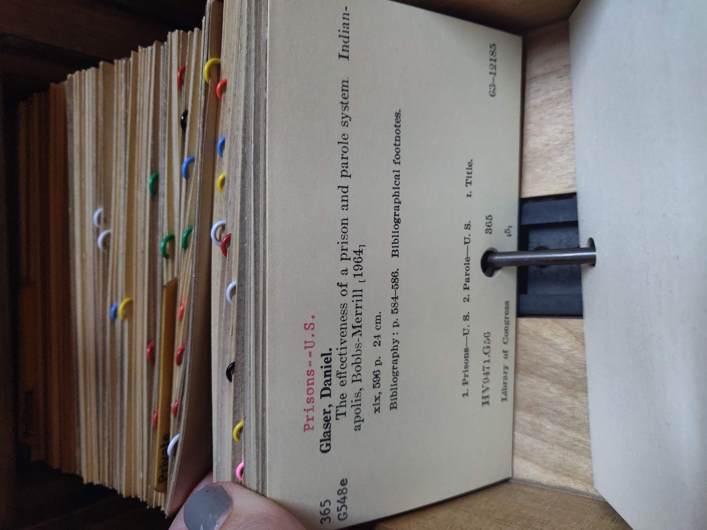 A drawer of a library card catalogue pulled open, showing handwritten catalogue cards with a bibliographic reference.